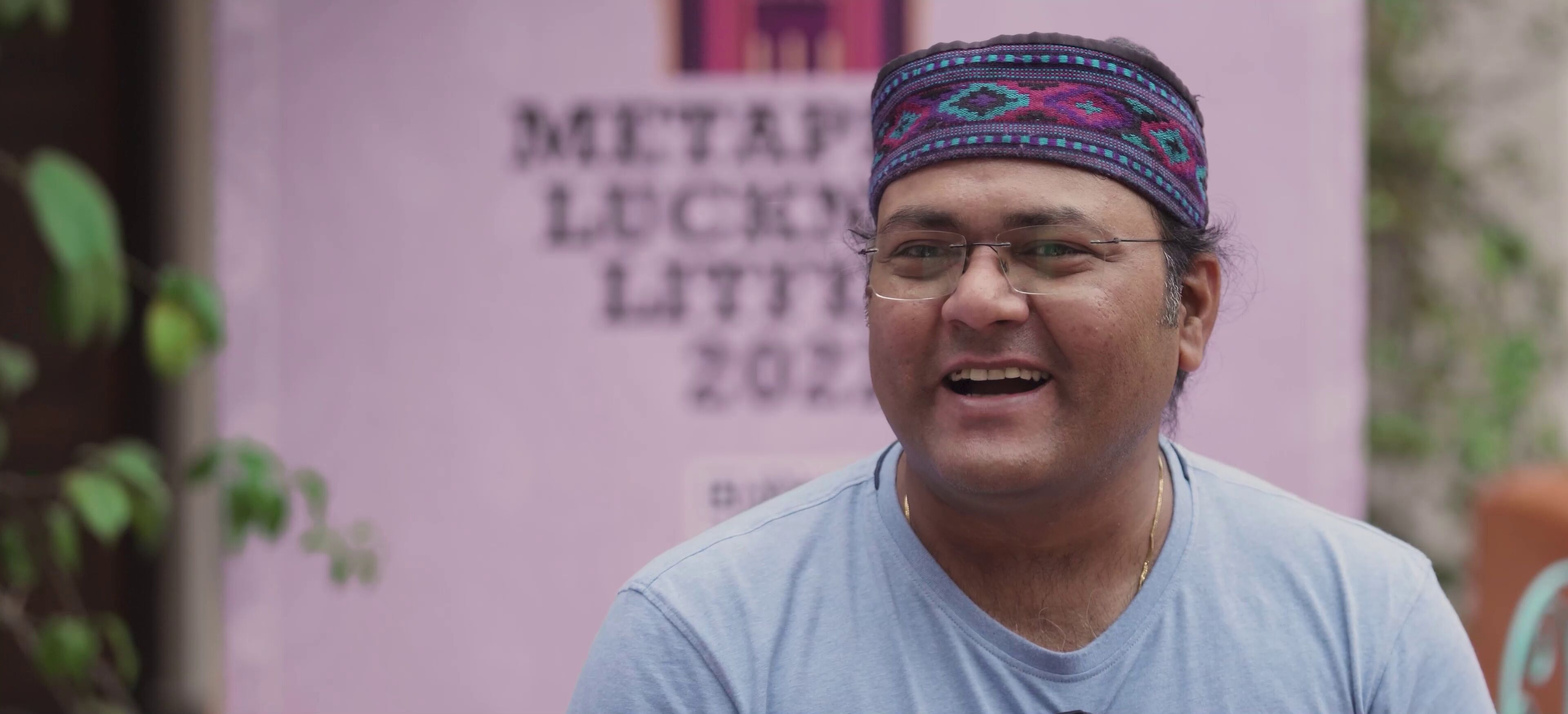A festival attendee in traditional Awadhi headwear listening to a discussion